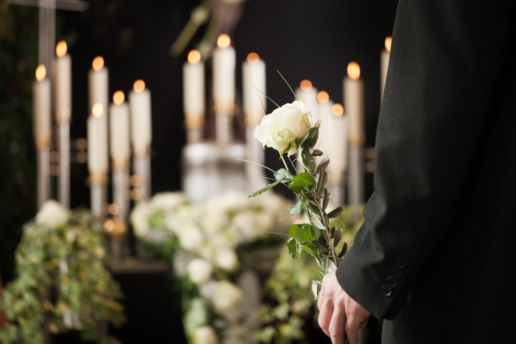 Man holding a white rose in front of urn at Arvin wrongful death funeral
